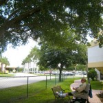 A rehabilitation patient rests his legs on a bench and takes a snooze under an oak canopy. Benches offer stopping points for respite along a path, even for wheelchair users.